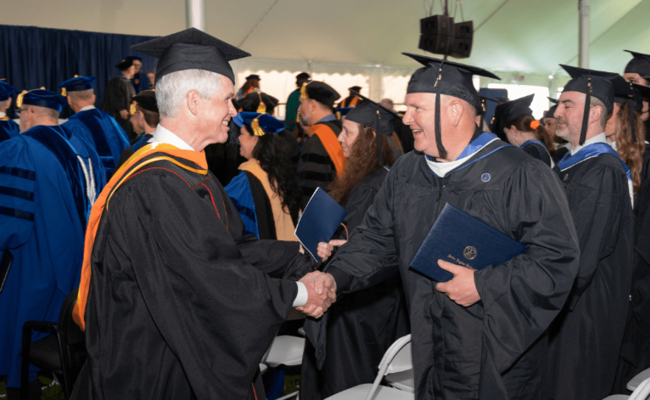 Salve Regina University Graduate Commencement professor shaking hand of graduate