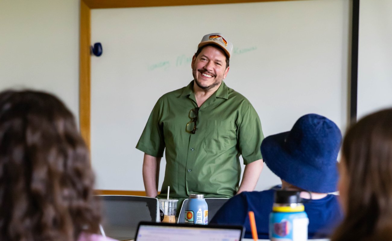 Professor at the front of the class engaging with students during an MFA writing workshop.