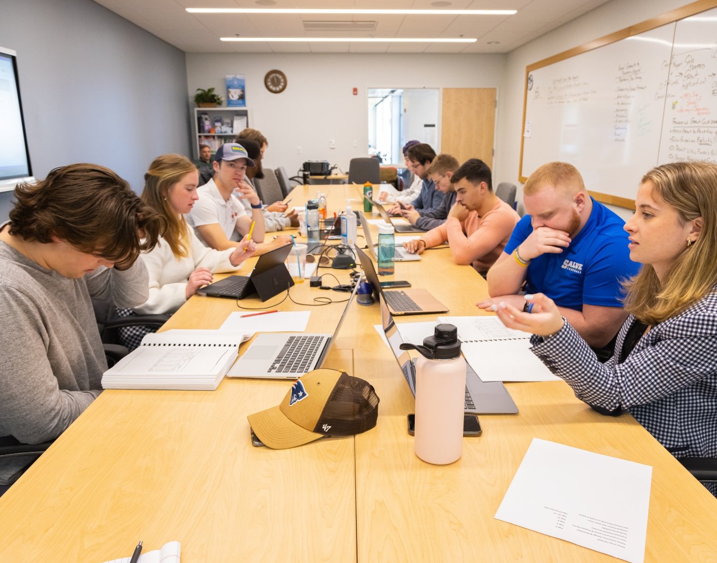 group of students sitting at table studying with laptops