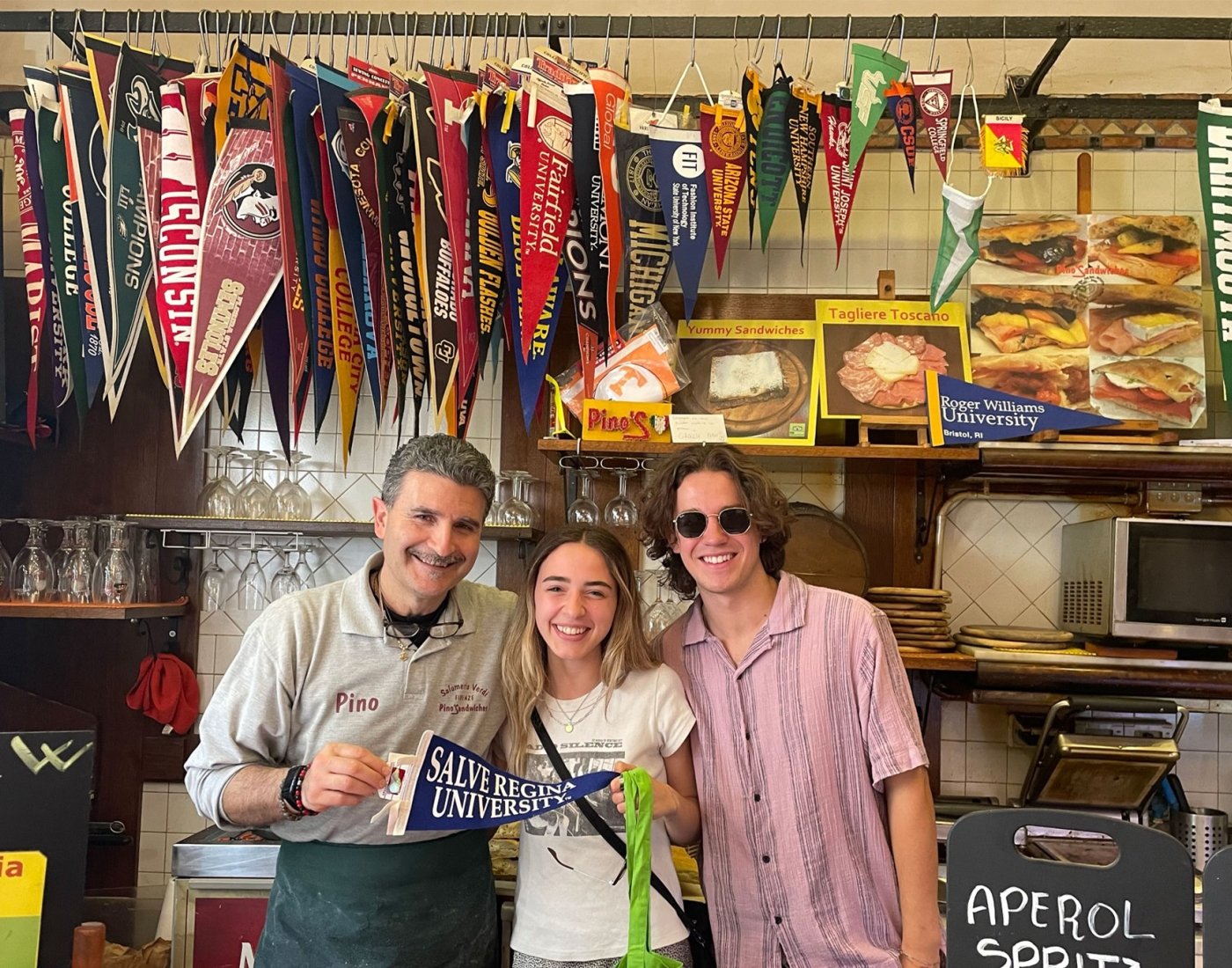 students pose with worker at restaurant in Italy