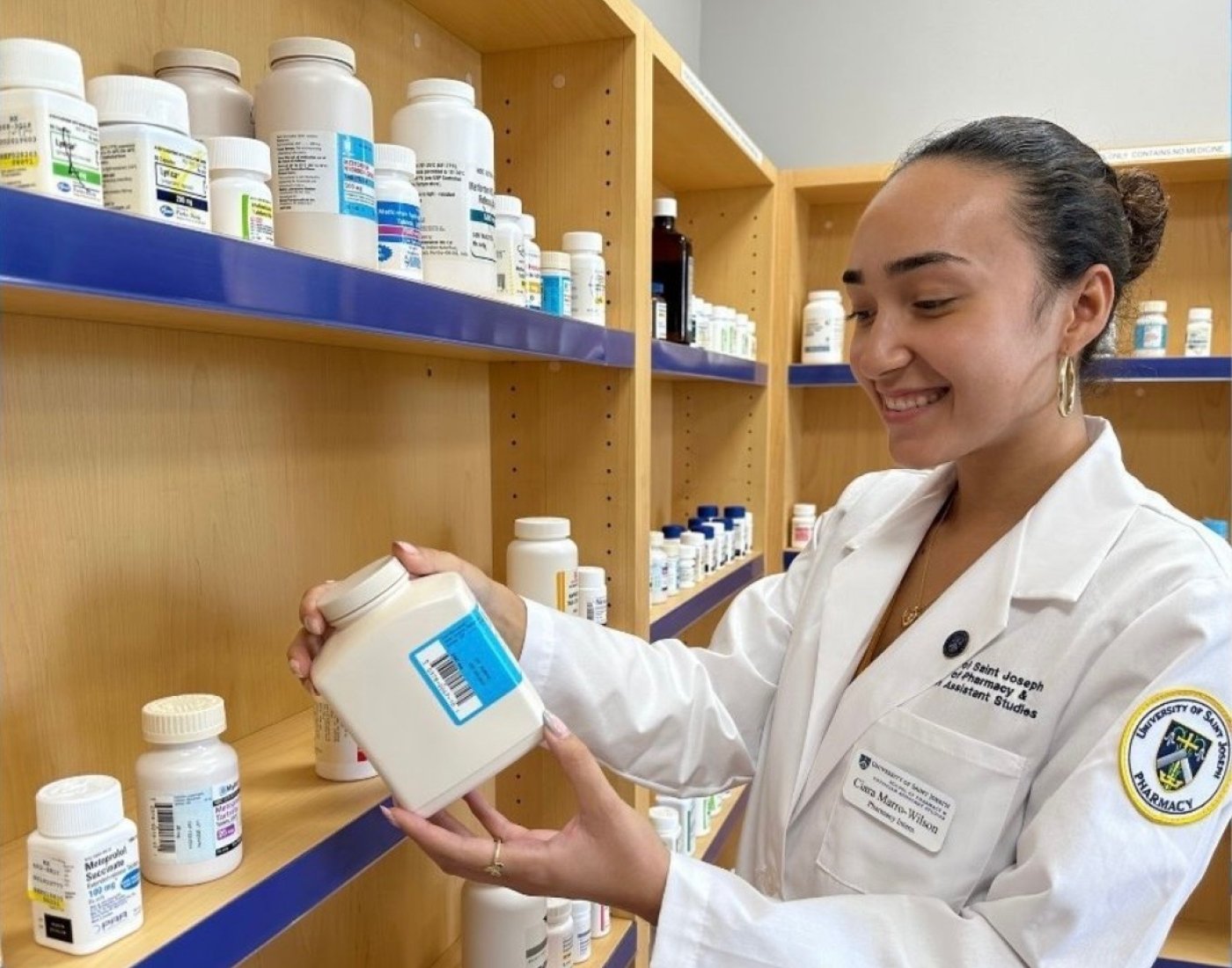 Marro-Wilson in white lab coat looking at a pill bottle.