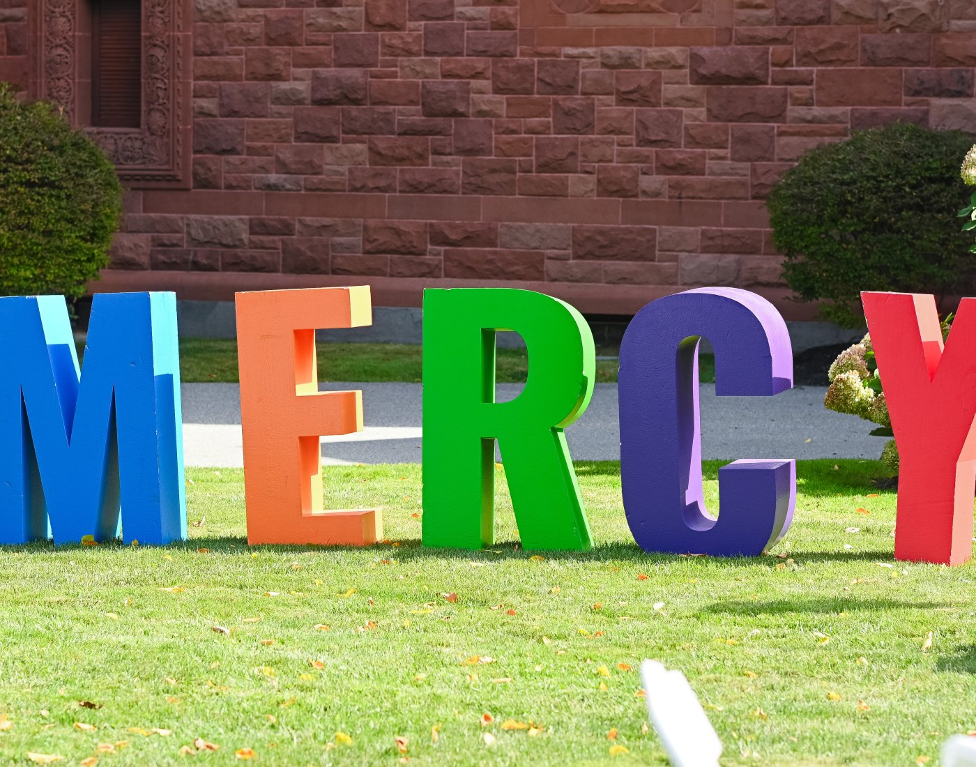 Large colorful letters that spell out 'MERCY' on the lawn.
