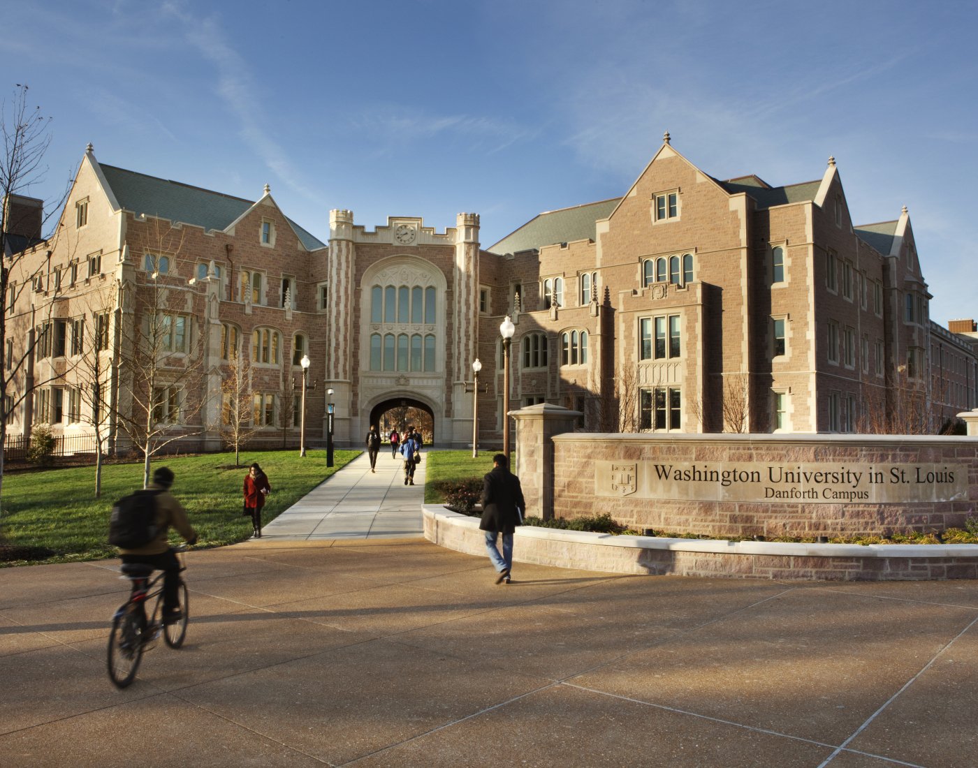 Washington University building exterior with students walking and biking outside.
