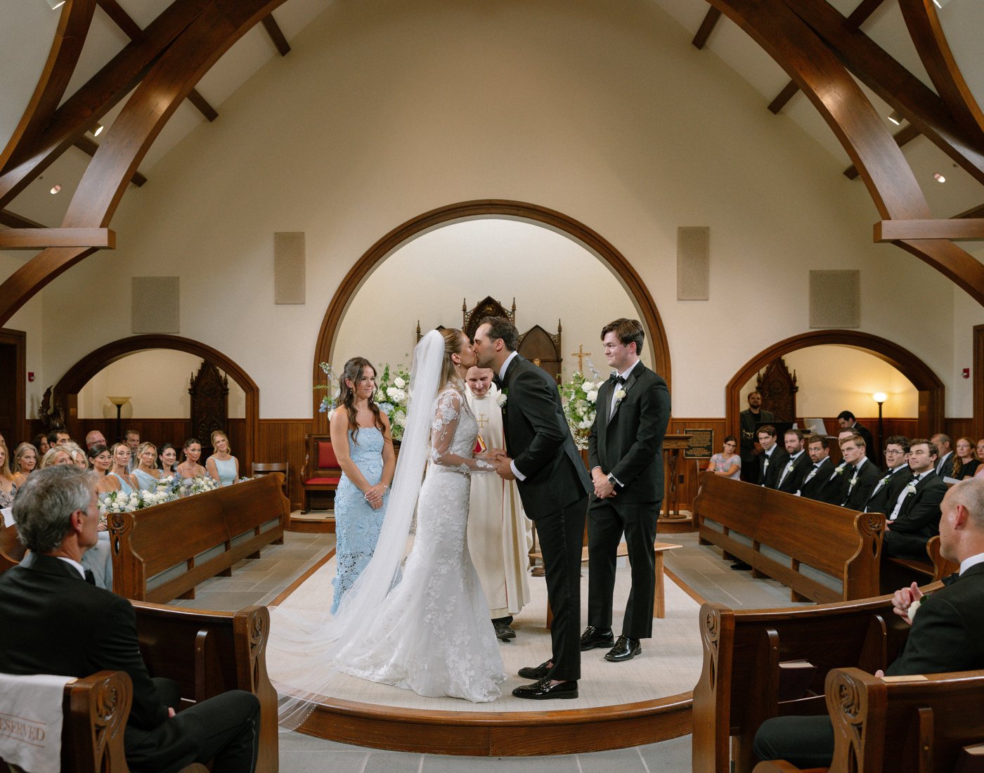A bride and groom kiss at the altar during a wedding ceremony in a church.