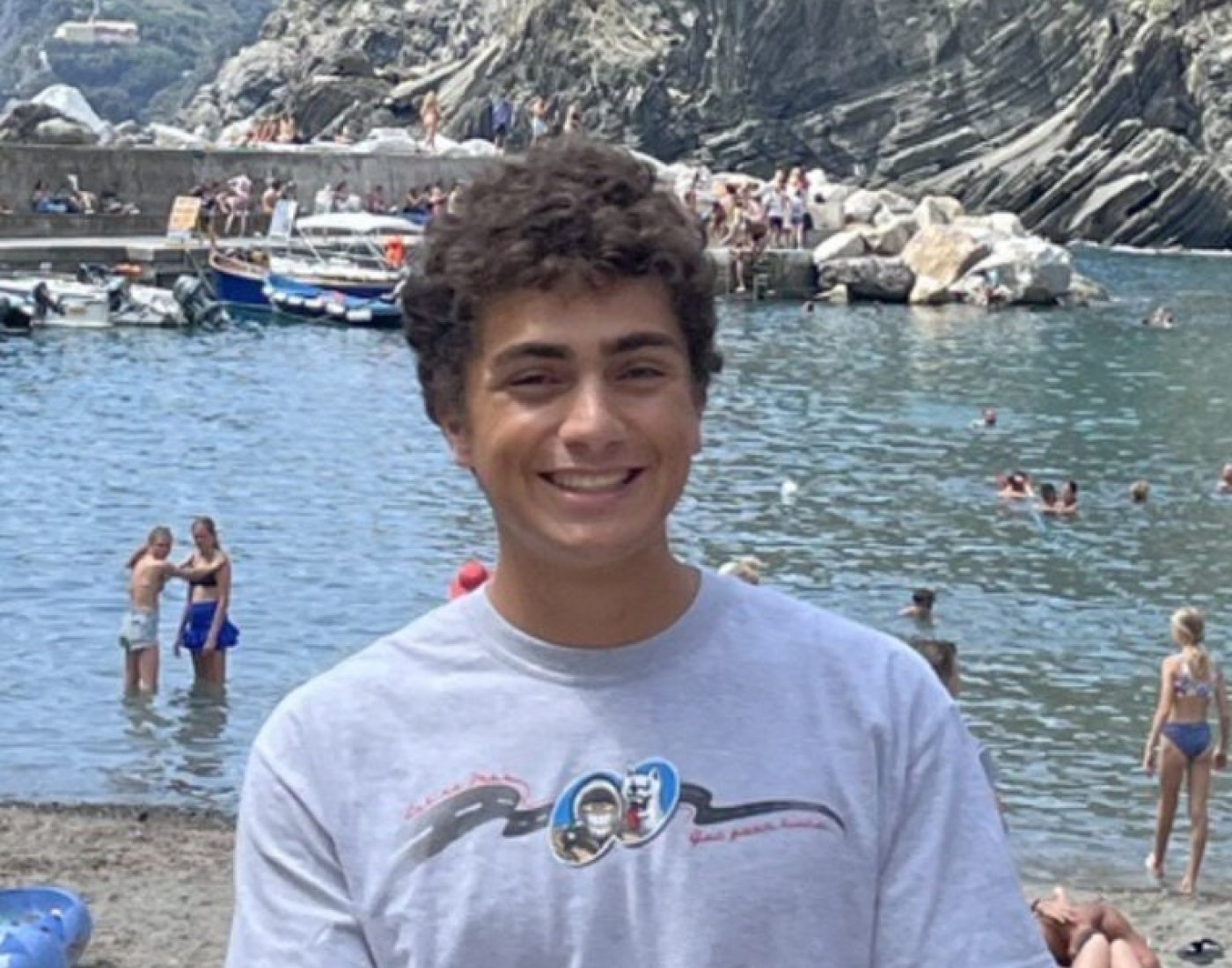 Male student giving a thumbs-up sign in front of a lake in Italy 