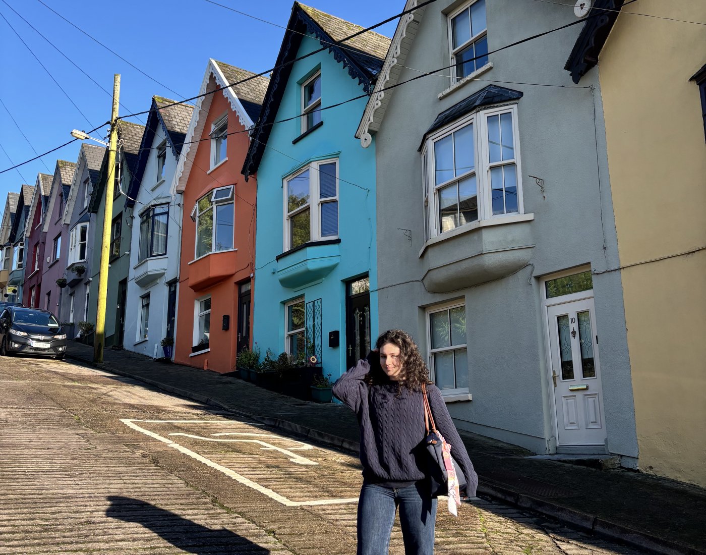 A student posed in the road in front of a row of brightly-painted houses