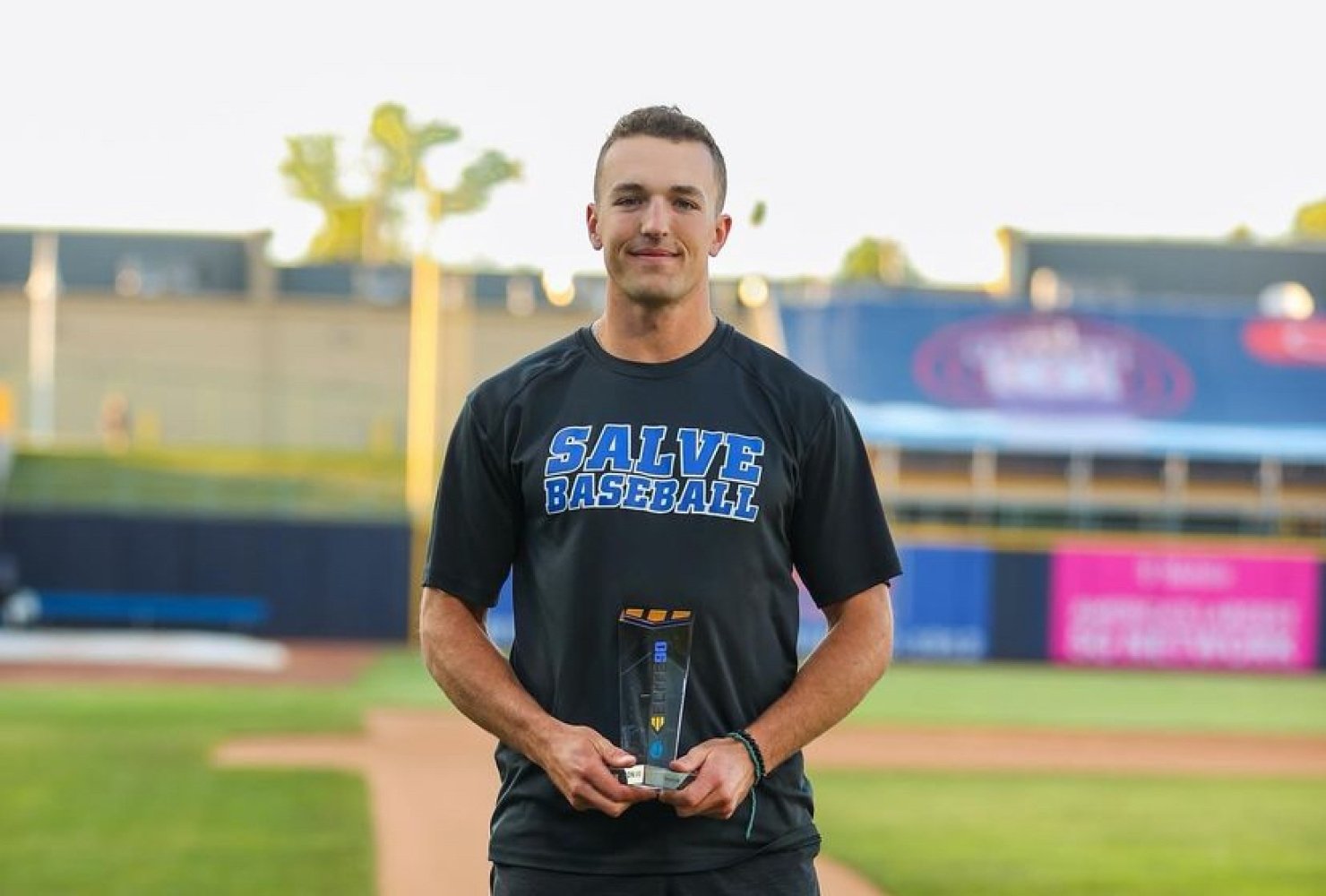 Brandon Grover standing on the baseball field holding a trophy