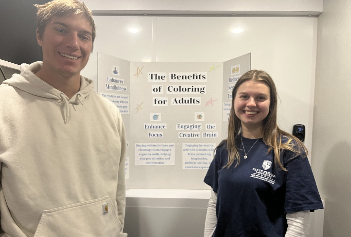Anderson and man standing in front of a poster board smiling.