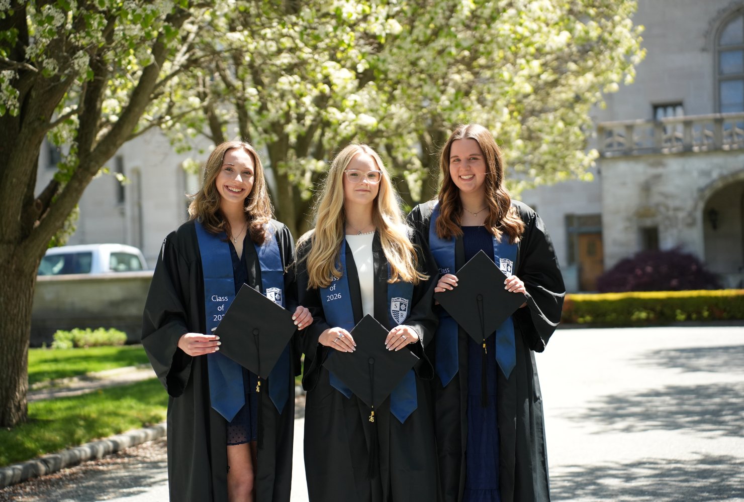 Group photo of the three valedictorians in their regalia outside of Ochre Court