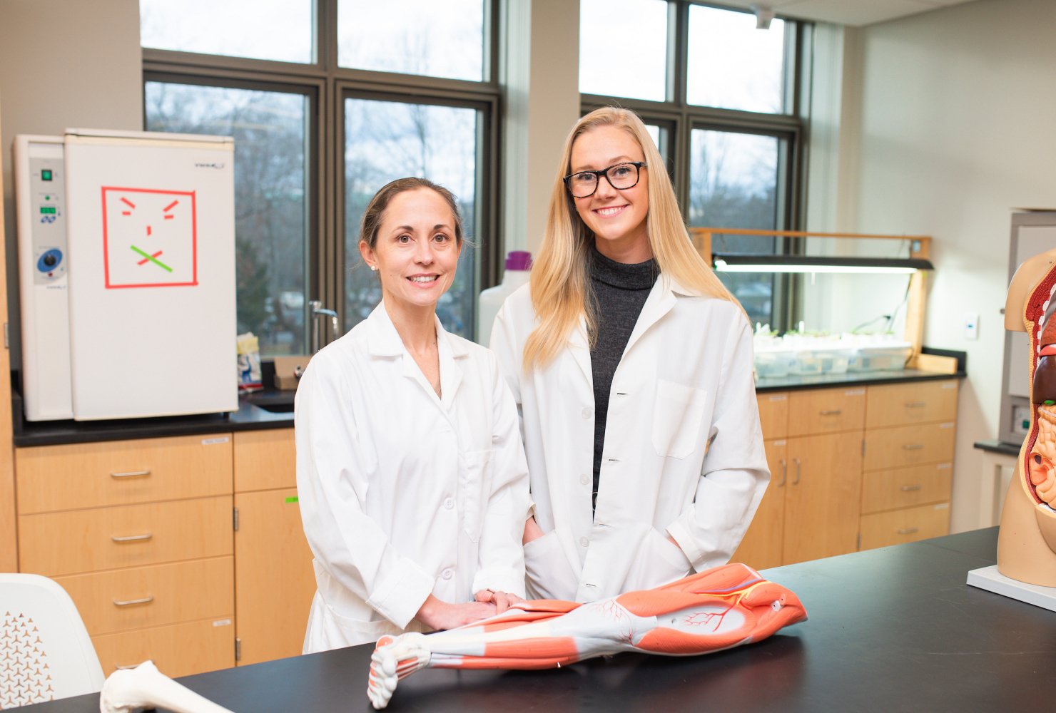Curesky and student in the lab with their lab coats on