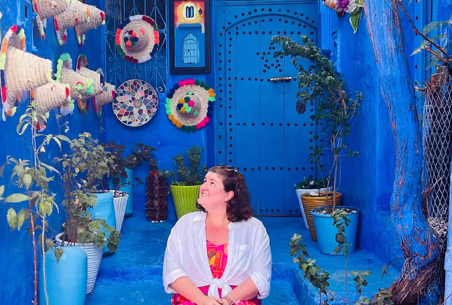 Student sitting in a colorful doorway with Moroccan objects 