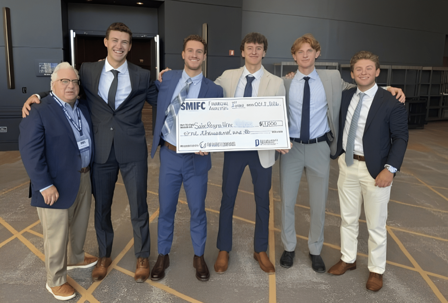 Professor and students posing with oversized check.