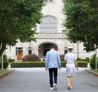 Navy officer and a man in a blue suit walking towards Ochre Court