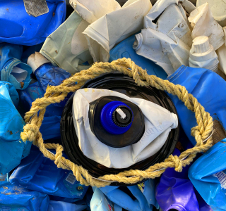 An art piece made from recyclables that features a large eye in the center.