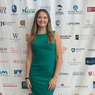 A woman in a green dress standing in front of a step and repeat