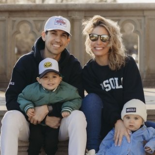 Photo of John Toracinta sitting outside of Ochre Court with his wife and children. All wearing NOSOLO apparel. 