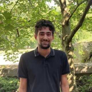 Photo of Jacob Oliveira smiling at the camera under the shade of a tree.
