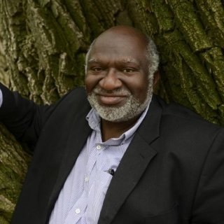 Headshot of Charles Coe leaning against the trunk of a tree