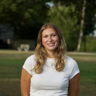 Professional photo of Luczak smiling in white t-shirt, in front of green field.