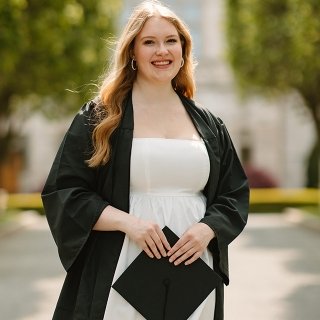 Professional photo of Pier smiling in graduation gown in front of Ochre Court