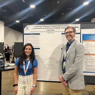 Photo of Caitlyn Ziolkowski and Dr. Cody Morris smiling in front of a poster with Caitlyn's research 