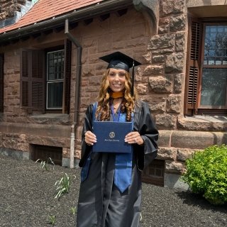 Sandra Mota in graduate regalia holding her diploma