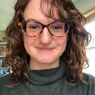 Headshot of Mary in glasses and turtleneck.