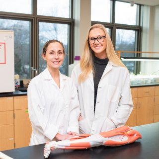 Curesky and student in the lab with their lab coats on