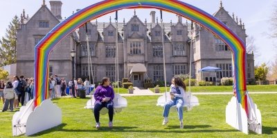 students on swings under rainbow arch