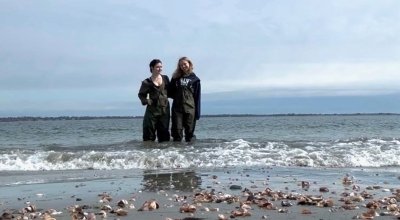 Two women standing in the water along a shoreline