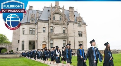 A line of people in graduation gowns walking down a sidewalk