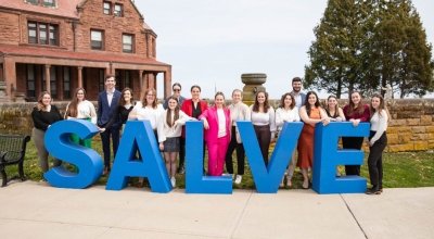 A group of people standing behind blue letters that spell out Salve