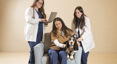 Nursing students sitting and standing, running 'tests' on dog for photoshoot image.