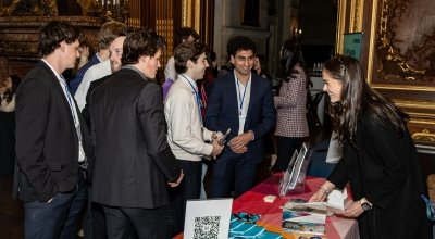 Male business students dressed professionally talking with businesswoman at a table for the Career and Internship Expo
