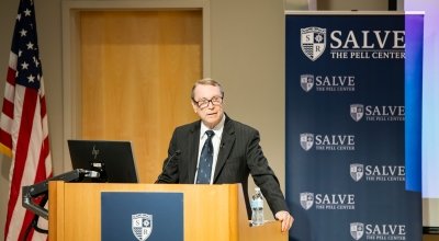 Craig Symonds standing at a podium giving his McGinty Lecture, with Salve branding and an American flag behind him.