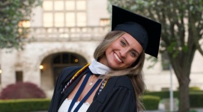 Valedictorian Jenna Martin in front of Ochre Court in her cap and gown.