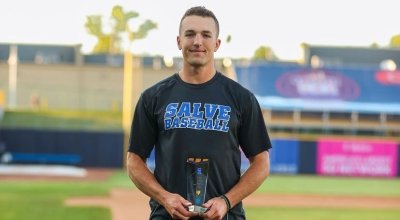 Brandon Grover standing on the baseball field holding a trophy