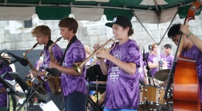 students in purple tie dye shirts playing jazz instruments at the Newport Jazz Festival