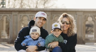 A family photo sitting on steps with John, Sarah and their two kids on their laps.