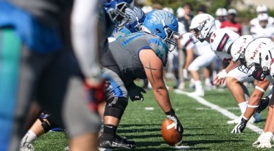 Football player holding ball in position at beginning of play.