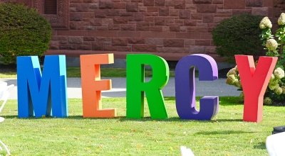 Large colorful letters that spell out 'MERCY' on the lawn.