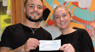 two students smiling holding a heck after winning $4,000 in hackathon competition.