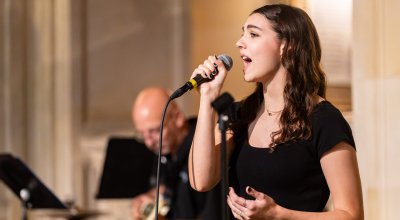 Professional photo of Julia singing into a microphone