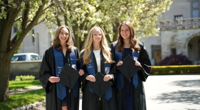 Group photo of the three valedictorians in their regalia outside of Ochre Court