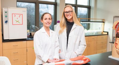 Curesky and student in the lab with their lab coats on