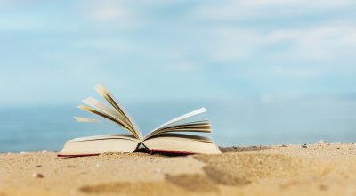 Book laying on the sand at the beach.