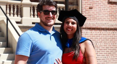 Natalie Buddiga poses with her husband in doctoral regalia at graduation.