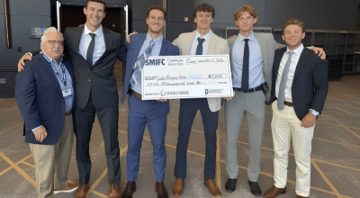 Professor and students posing with oversized check.