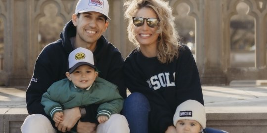 Photo of John Toracinta sitting outside of Ochre Court with his wife and children. All wearing NOSOLO apparel. 