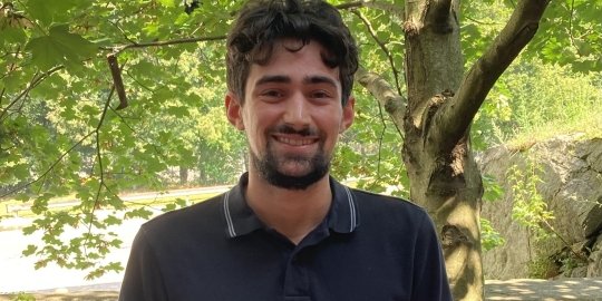 Photo of Jacob Oliveira smiling at the camera under the shade of a tree.